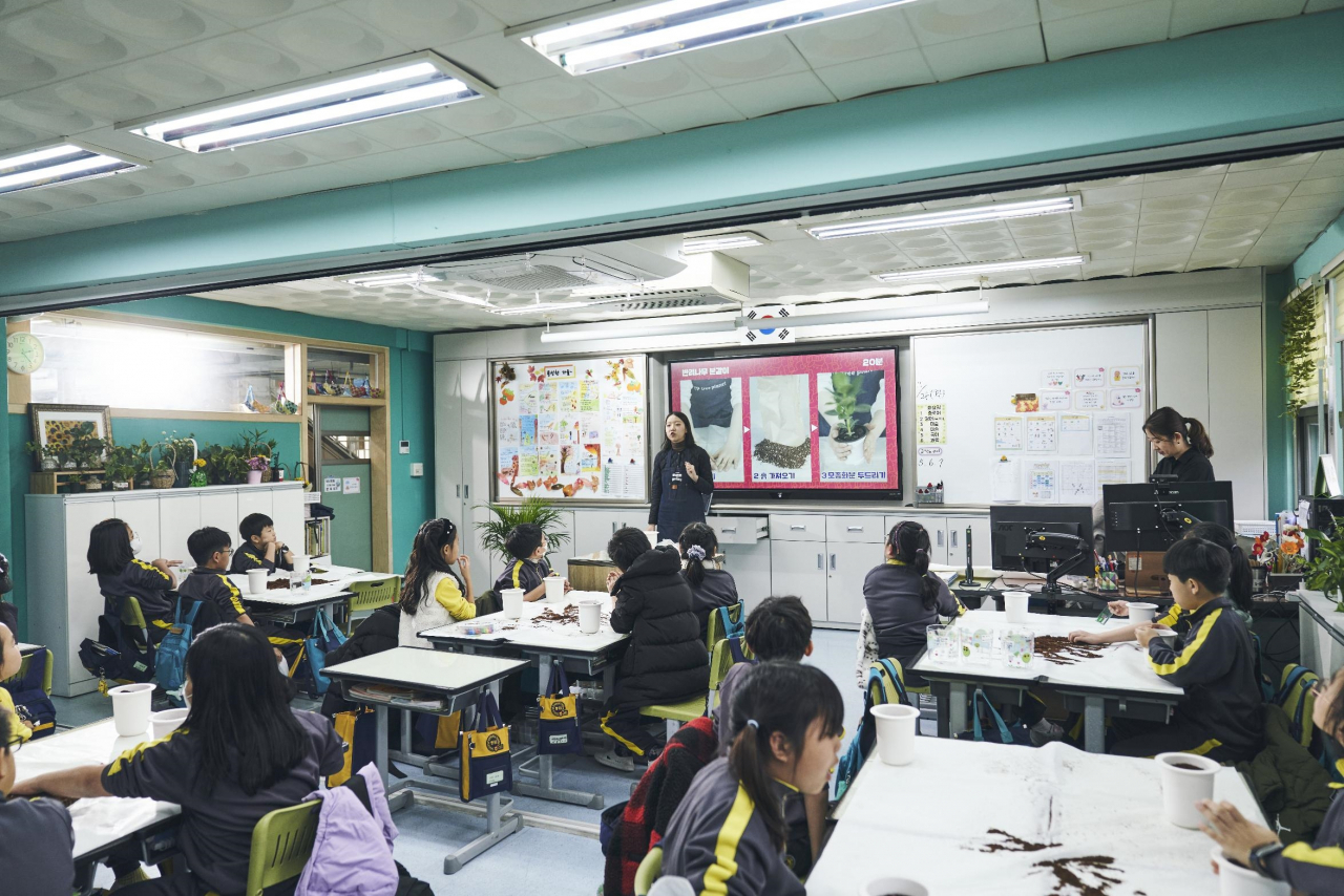 현대글로비스 직원들이 ‘교실 숲 조성 봉사활동’에 참가해 초등학생들에게 식물을 나눠주고 있다. [현대글로비스 제공]