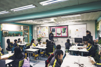 현대글로비스 직원이 ‘교실 숲 조성 봉사활동’에 참가해 초등학생에게 식물을 나눠주고 있다. [현대글로비스 제공]