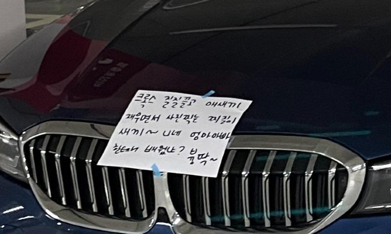 전기차 충전기에 '대기' 상태로 꽂아만 두고 장기간 차를 세운 차량이 전기차 충전구역 주차 위반 신고를 당하자 본인 차량 앞에 신고자를 욕한 메시지를 붙여 놓은 모습. [온라인 커뮤니티 '보배드림' 갈무리]