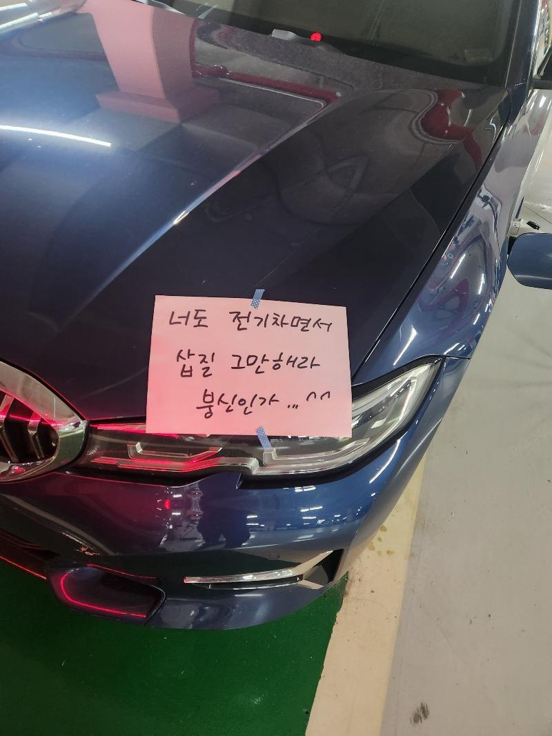 전기차 충전기에 '대기' 상태로 꽂아만 두고 장기간 차를 세운 차량이 전기차 충전구역 주차 위반 신고를 당하자 본인 차량 앞에 신고자를 욕한 메시지를 붙여 놓은 모습. [온라인 커뮤니티 '보배드림' 갈무리]
