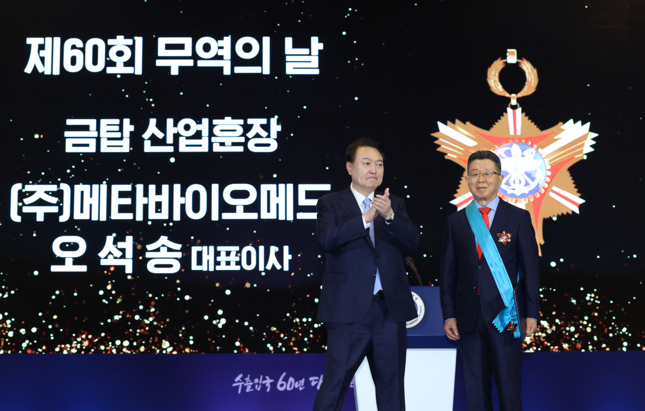 윤석열 대통령이 5일 서울 강남구 코엑스에서 열린 제60회 무역의날 기념식에서 오석송 메타바이오메드 대표이사에게 금탑산업훈장을 수여한 뒤 박수를 보내고 있다. [연합]