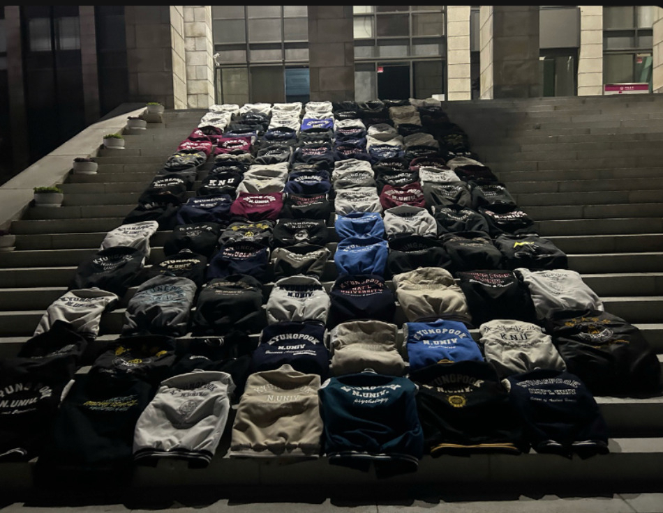 경북대 본관 앞 계단에 학생들이 벗어놓은 학과 점퍼가 줄 맞춰 가지런히 펼쳐져 있다. 재학생들은 금오공대와의 통합에 반대하며 '과잠시위'를 벌이고 있다. [에펨코리아 갈무리]