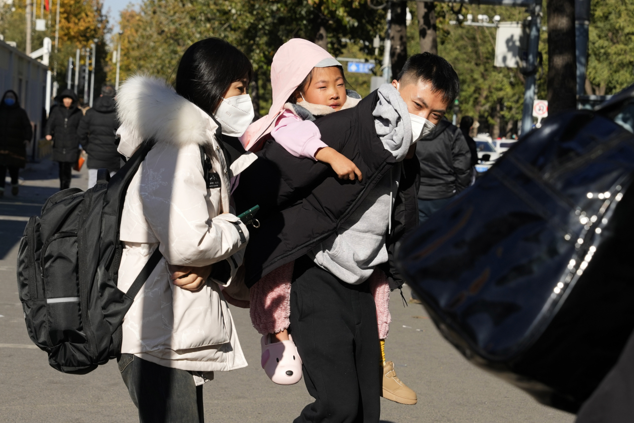 중국에서 시민이 아이를 업은 채로 소아과 병동을 나서고 있다. [AP]