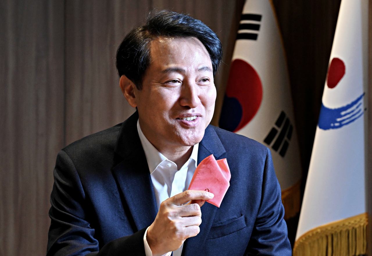 Seoul Mayor Oh Se-hoon poses for a photo during an interview with The Korea Herald at Seoul City Hall, showing a “sky coral” handkerchief, the color his administration chose as this year‘s “Color of Seoul,” derived from the pink sky when the sun sets over the Han River. (Im Se-jun/The Korea Herald)