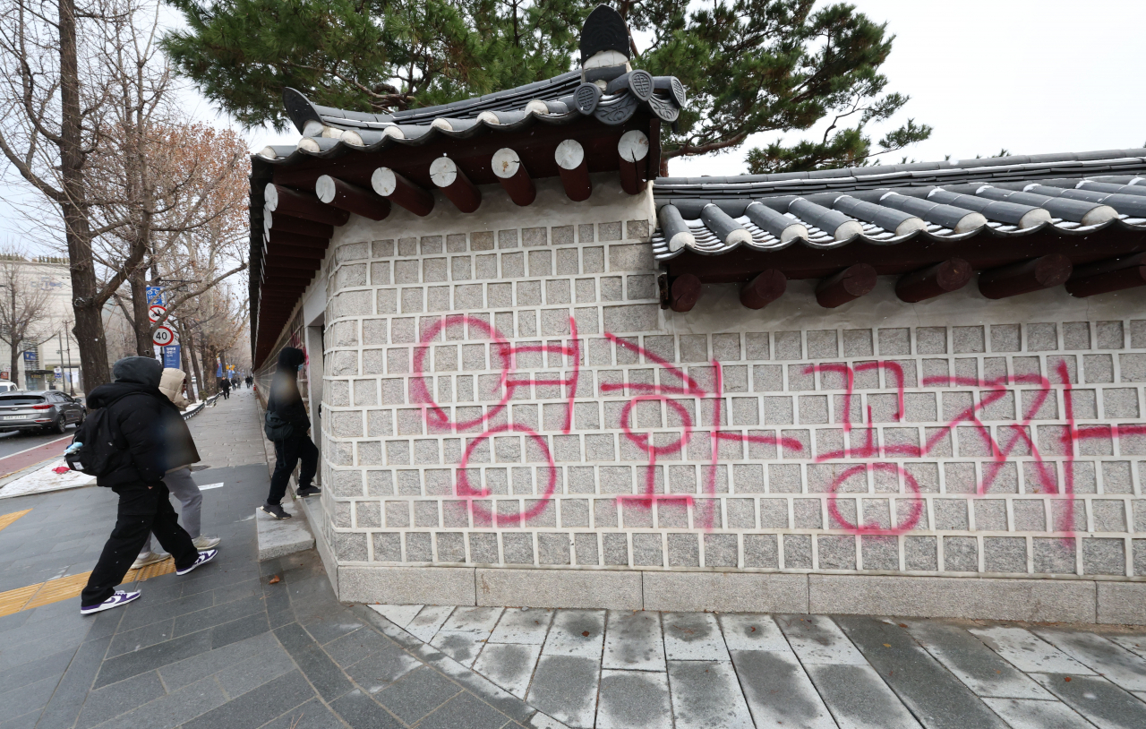 Pedestrians look at red and blue graffiti that reads "free movie" sprayed on the walls of Gyeongbok Palace in Seoul on Saturday (Yonhap)
