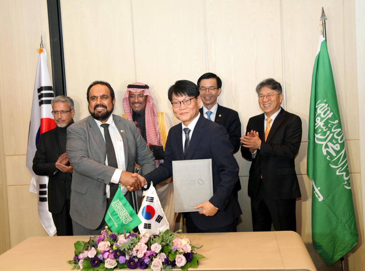 KG 모빌리티 정용원(앞줄 오른쪽) 대표이사와 SNAM사 파하드 알도히시 사장이 MOU를 체결하고 악수를 하고 있다. KG 모빌리티 곽재선(뒷줄 오른쪽부터) 회장, 산업통상자원부 방문규 장관, 사우디 산업광물자원부 반다르 이브라임 알코라이예프 장관, SNAM사 무함마드 알 트와이즈리 회장. [KG 모빌리티 제공]
