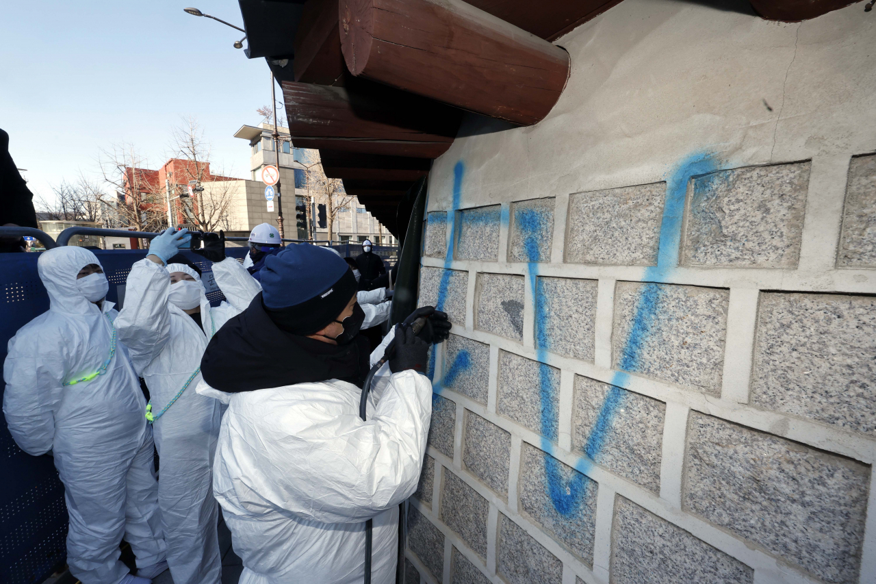 17일 오전 서울 종로구 국립고궁박물관 쪽문 경복궁 담벼락 앞에서 문화재청 관계자들이 전날 누군가가 스프레이로 쓴 낙서 제거 작업을 하고 있다. [연합뉴]