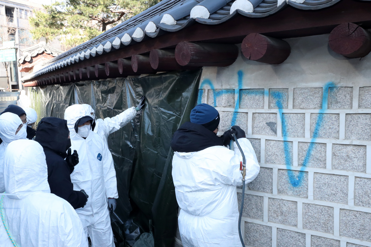 17일 오전 서울 종로구 국립고궁박물관 쪽문 경복궁 담벼락 앞에서 궁능유적본부 관계자들이 전날 누군가가 스프레이로 쓴 낙서 제거 작업을 하고 있다. [연합]