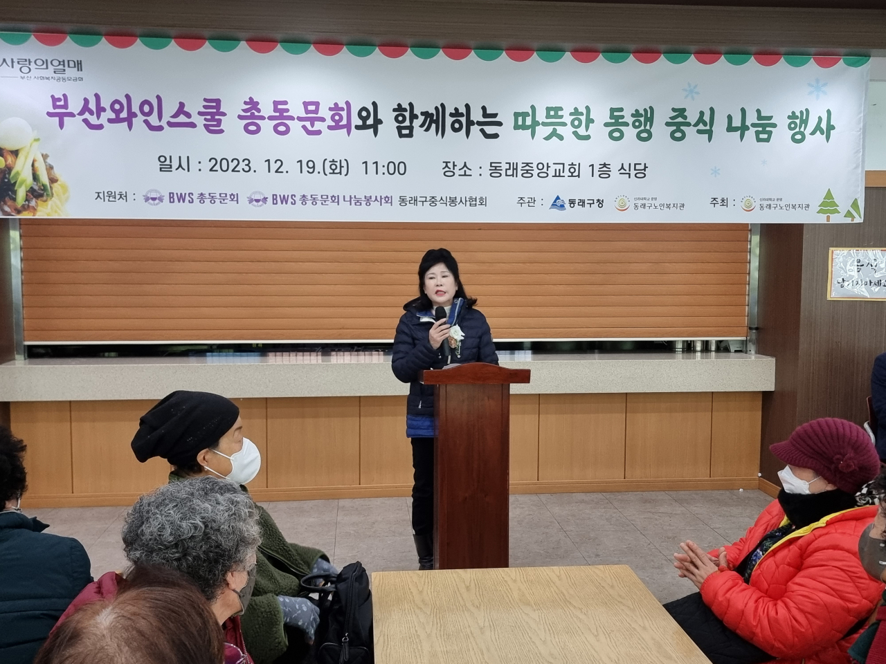 부산와인스쿨 총동문회 박철심 회장이 19일 동래중앙교회 1층 식당에서 열린 ‘부산와인스쿨 총동문회와 함께하는 따뜻한 동행 중식 나눔 행사’에서 어드신들에게 “따뜻한 겨울나세요”라고 인사말을 하고 있다. [사진=임순택 기자]