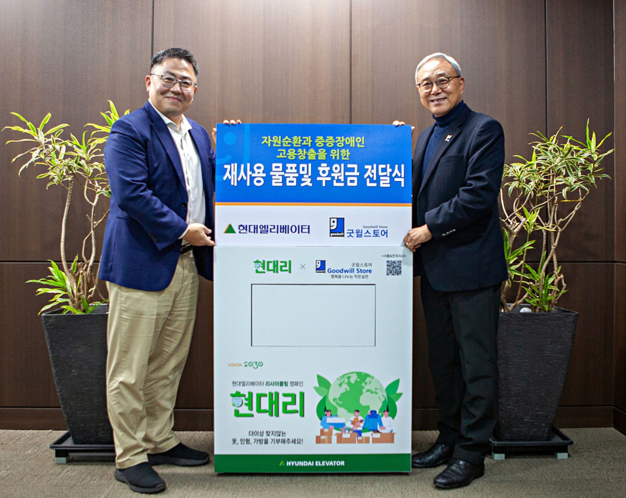 이용운(왼쪽) 현대엘리베이터 CSO가 한상욱 굿윌스토어 본부장에게 임직원 기부물품과 ‘장애인 일터 건립 후원금’을 전달하고 있다. [현대엘리베이터 제공]