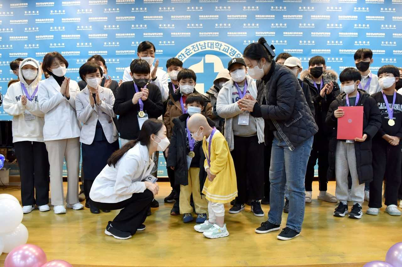 화순전남대병원 ‘제23회 소아암·백혈병 희귀질환 완치잔치’에서 김보람 소아청소년과 교수가 환아에게 완치 메달을 걸어주고 축하해주고 있다.