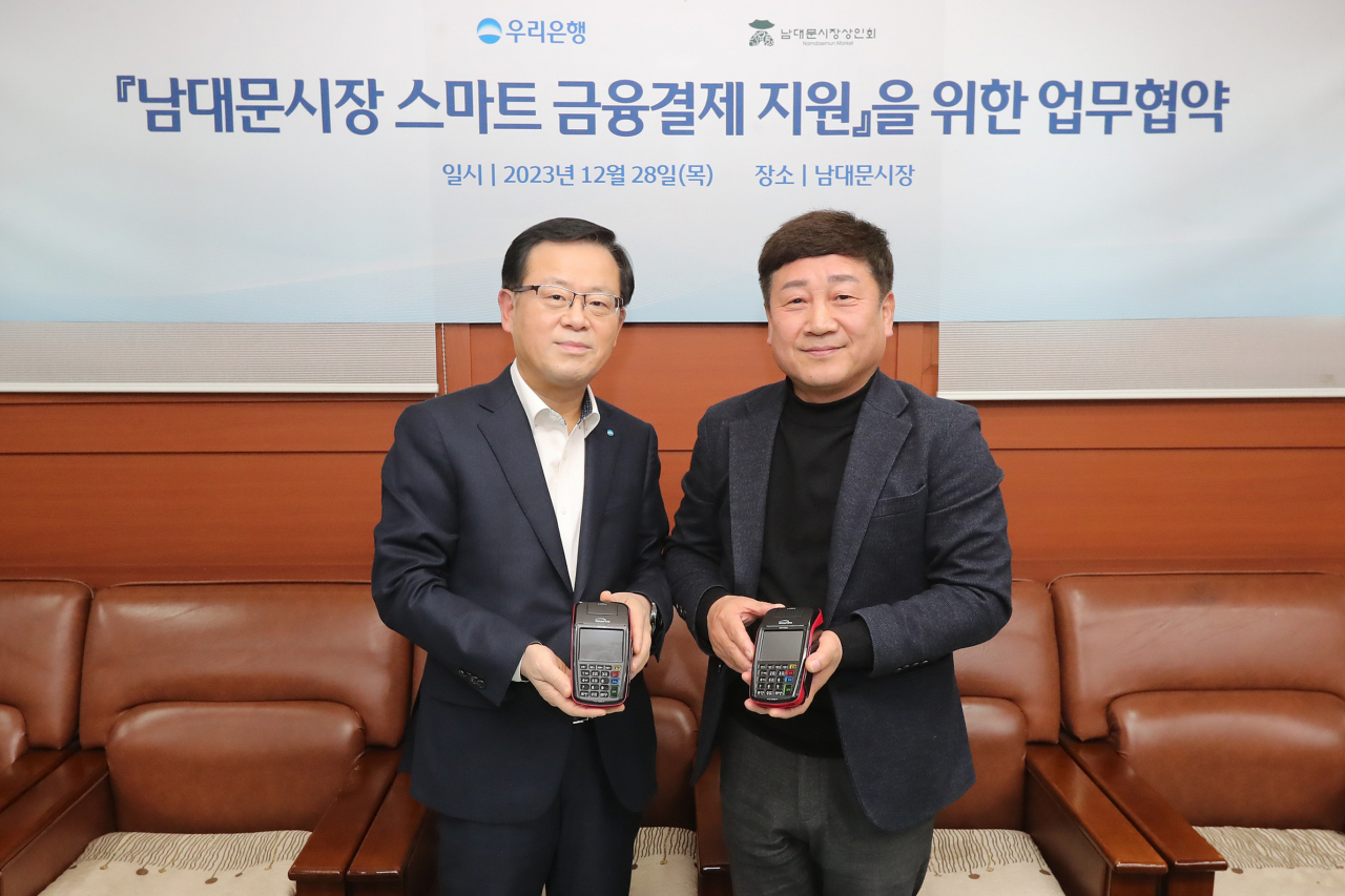 조병규 우리은행장(왼쪽)은 28일 문남엽 남대문시장상인회장을 만나 민생금융지원방안 중 자율프로그램의 일환으로 ‘상생경영 및 동반성장을 위한 협약’을 체결하고 스마트 결제기기 지원을 통해 남대문시장 스마트 결제 인프라 구축을 지원하기로 했다. [우리은행 제공]