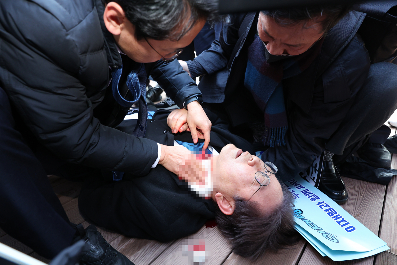 더불어민주당 이재명 대표가 2일 부산 가덕도 신공항 부지를 둘러본 후 기자들과 문답을 진행하던 중 왼쪽 목 부위에 습격을 당해 피를 흘린 채 쓰러져 있다. [연합]
