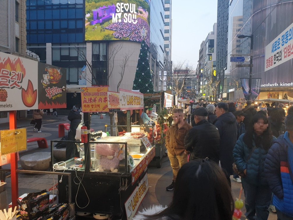 외국인 관광객들이 명동 노점 음식을 바라보고 있다.