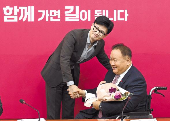 한동훈 국민의힘 비상대책위원장이 8일 오전 국회에서 열린 회의에서 이상민 의원의 입당을 축하하며 꽃다발을 전해주고 있다. 이상섭 기자