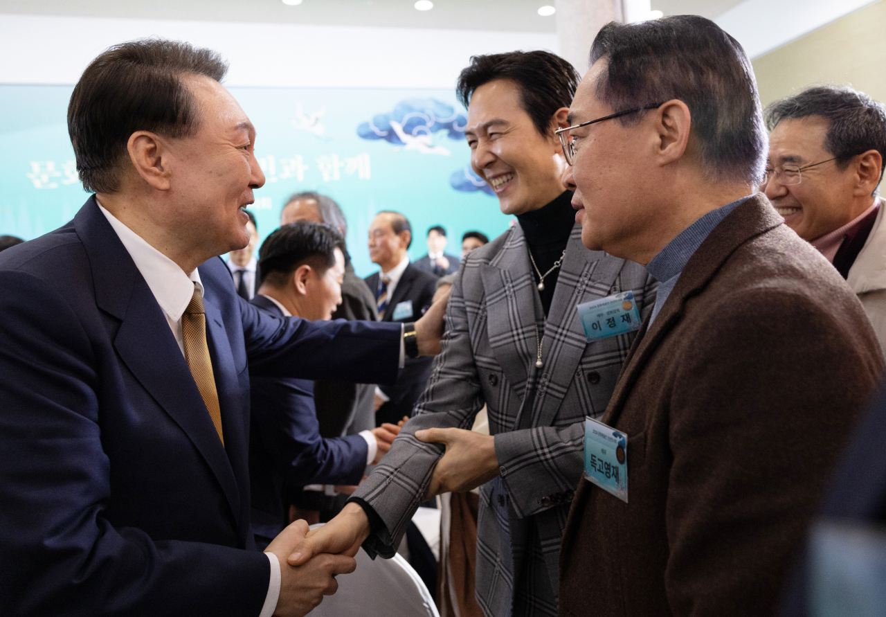 President Yoon Suk Yeol shakes hands with "Squid Game" star Lee Jung-jae at a New Year's gathering of South Korean artists and celebrities in Seoul on Tuesday. (Yonhap)