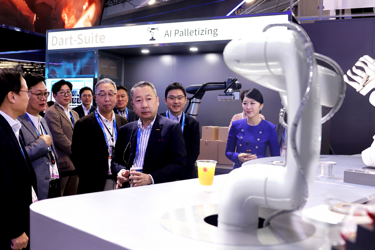 박정원 두산그룹 회장(가운데), 박지원 그룹부회장(왼쪽)이 10일(현지시간) CES 2024가 열리는 미국 라스베이거스 컨벤션센터를 찾아 두산 부스에서 인공지능(AI) 칵테일 로봇을 살펴보고 있다. [두산 제공]