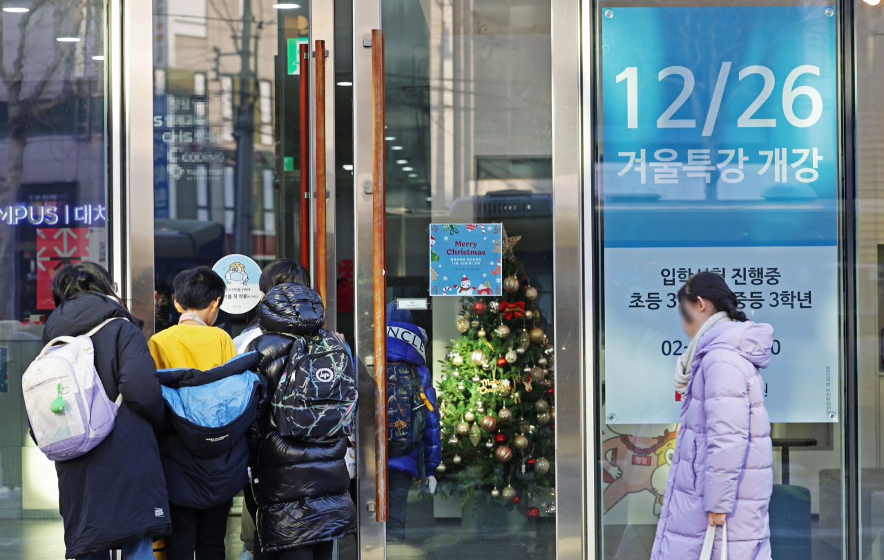 26일 오전 서울 시내 한 학원에서 학생들이 '겨울 특강 개강'이라고 적힌 안내문을 지나 들어서고 있다. [연합]