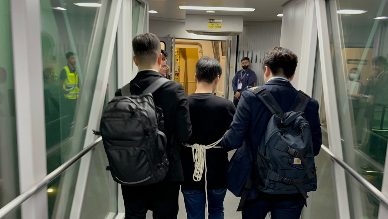 필리핀에서 검거된 피의자 A씨(가운데)가 17일 인천국제공항행 비행기에 오르고 있다. [경찰청 제공]
