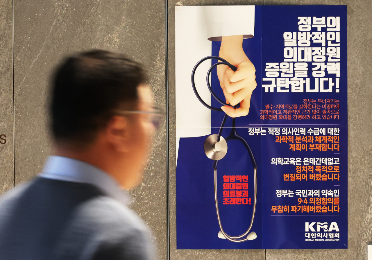 지난 17일 서울 용산구 대한의사협회 복도에서 관계자가 의협의 주장이 담긴 벽보 앞을 지나고 있다. [연합]