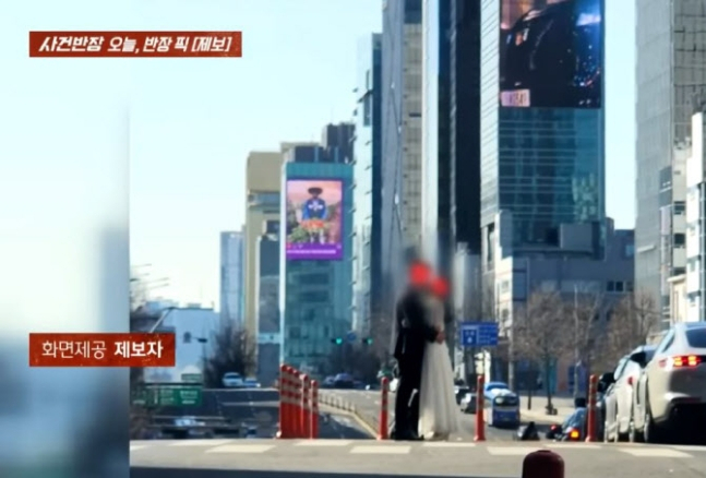 서울 강남 도산대로 한 가운데에서 턱시도와 웨딩드레스를 입은 남녀가 끌어 안고 입을 맞추고 있다. [JTBC 사건반장 갈무리]