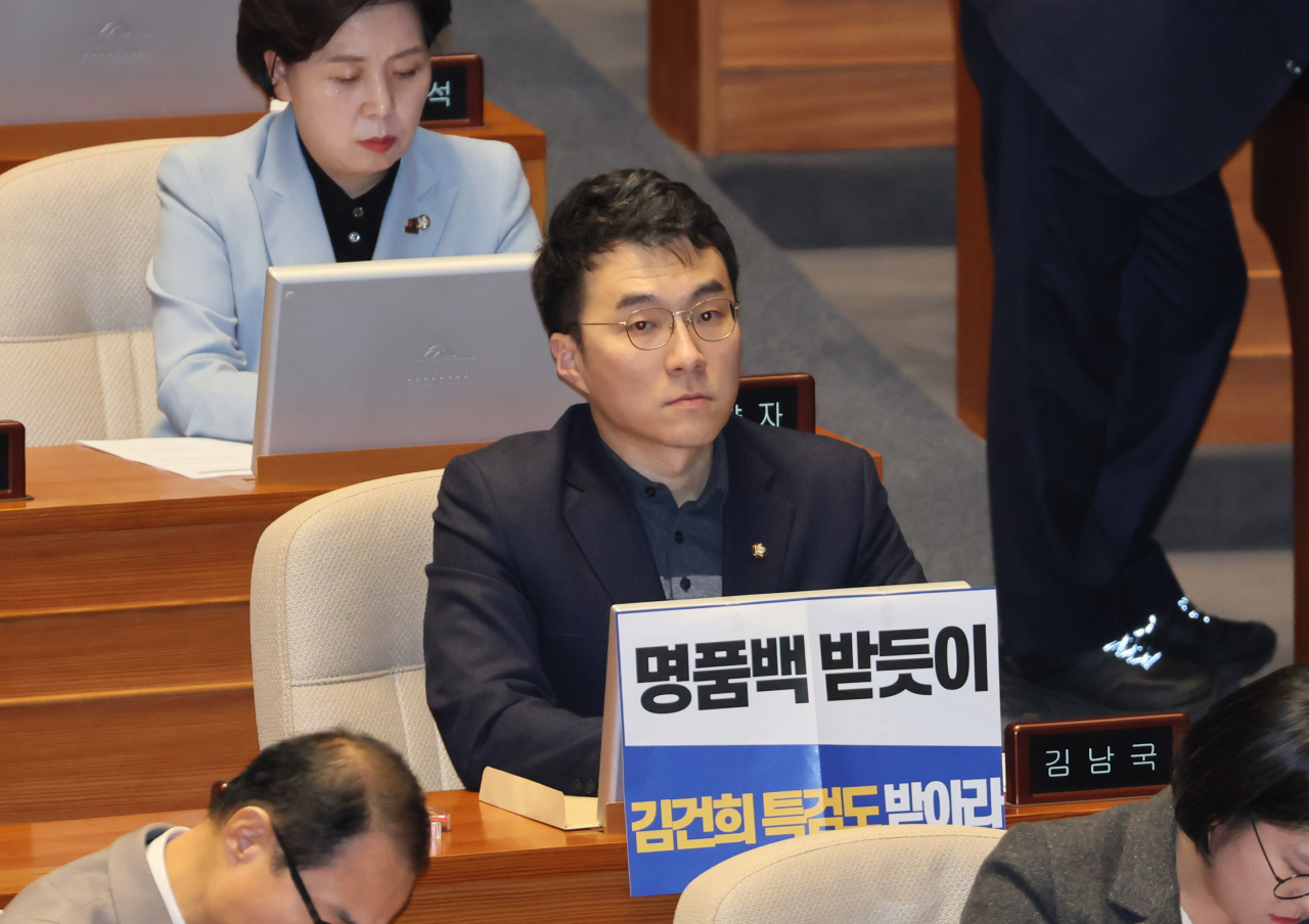 무소속 김남국 의원이 지난해 12월 28일 오후 국회 본회의에서 김건희 여사 특검법 수용을 촉구하는 손팻말을 붙이고 있다. [연합]