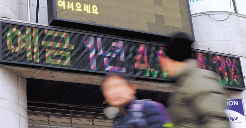 서울 시내 한 은행 금리 안내 전광판 앞을 시민들이 지나가고 있다. [연합]