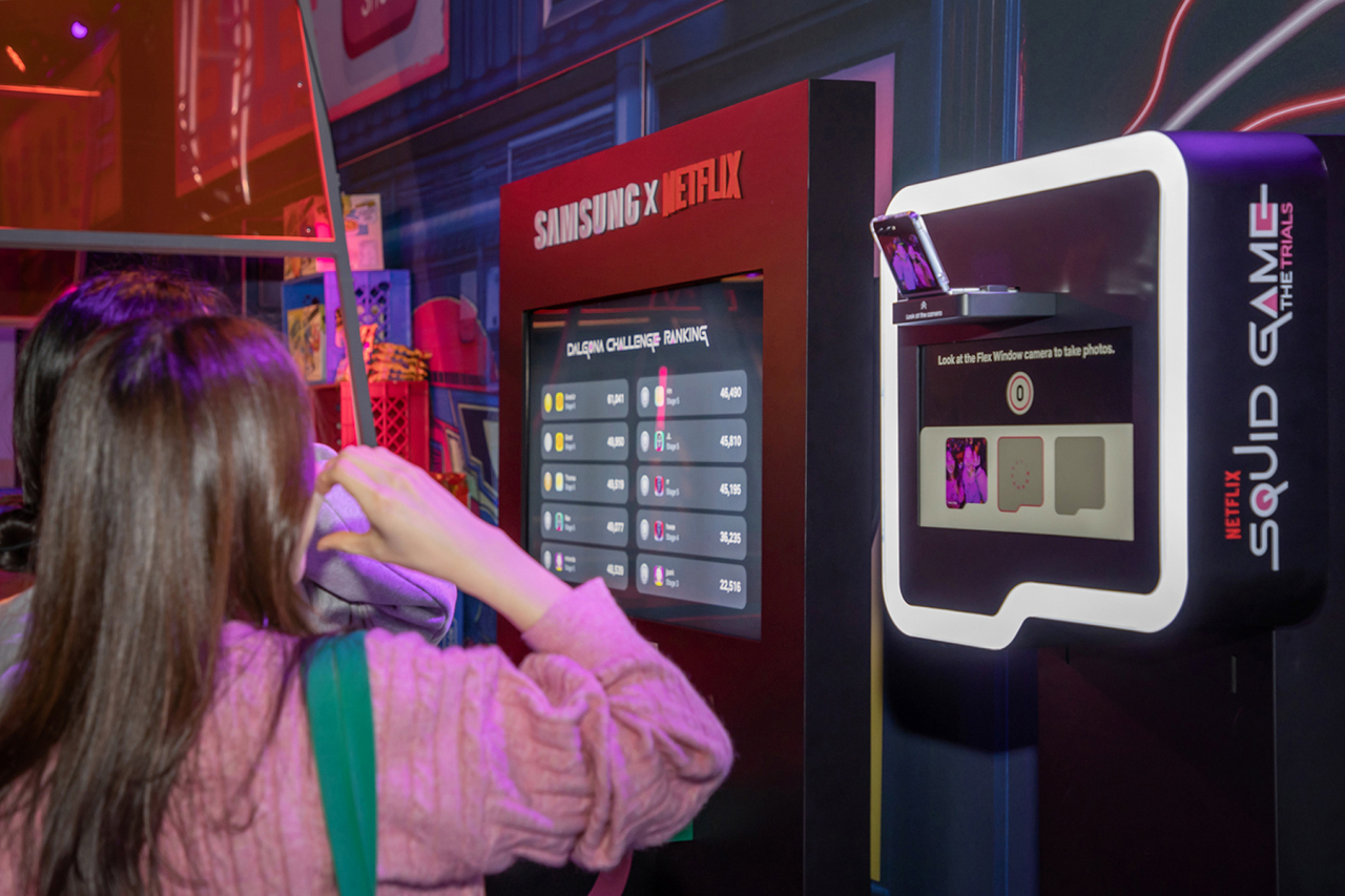 Visitors take photos with the Samsung Galaxy Z Flip5 at the “Squid Game: The Trials,” an immersive experience program in Los Angeles. (Samsung Electronics)