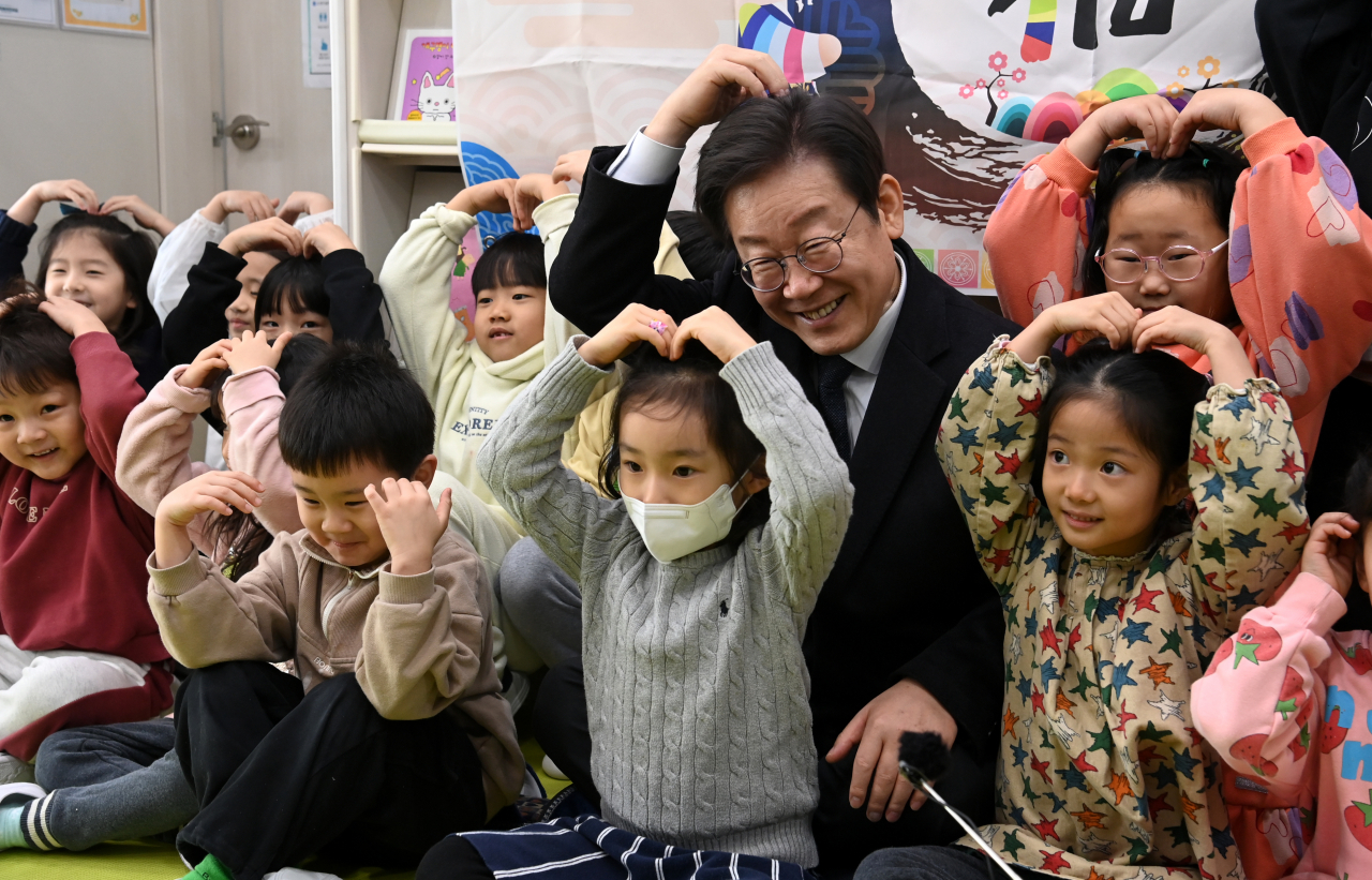 24일 경기 김포시 통진읍 청룡어린이집을 찾은 이재명 더불어민주당 대표가 어린이집 원아들과 함께 손 하트를 만들며 밝게 웃고 있다. [연합]