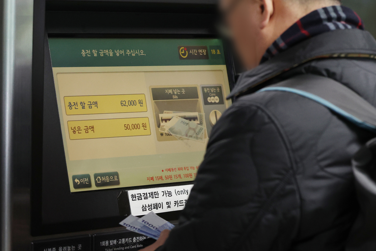 28일 서울 지하철에서 무제한 정기승차권인 ‘기후동행카드’를 현금으로 충전하고 있는 시민의 모습. 충전 기기에는 ‘현금 결제만 가능’ 이라고 써 있다. [연합]