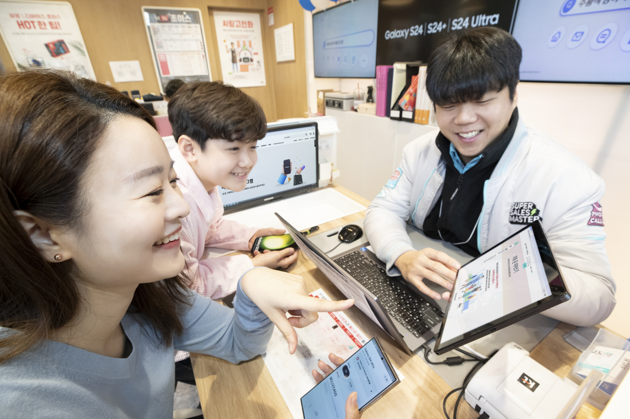 KT가 삼성전자와 함께 기존폰을 자녀에게 물려주는 ‘갤럭시 패밀리폰 프로그램’을 시행한다고 2일 밝혔다. KT플라자에서 엄마와 아들이 기존폰을 물려주고 받는 서비스를 소개받는 모습. [KT 제공]