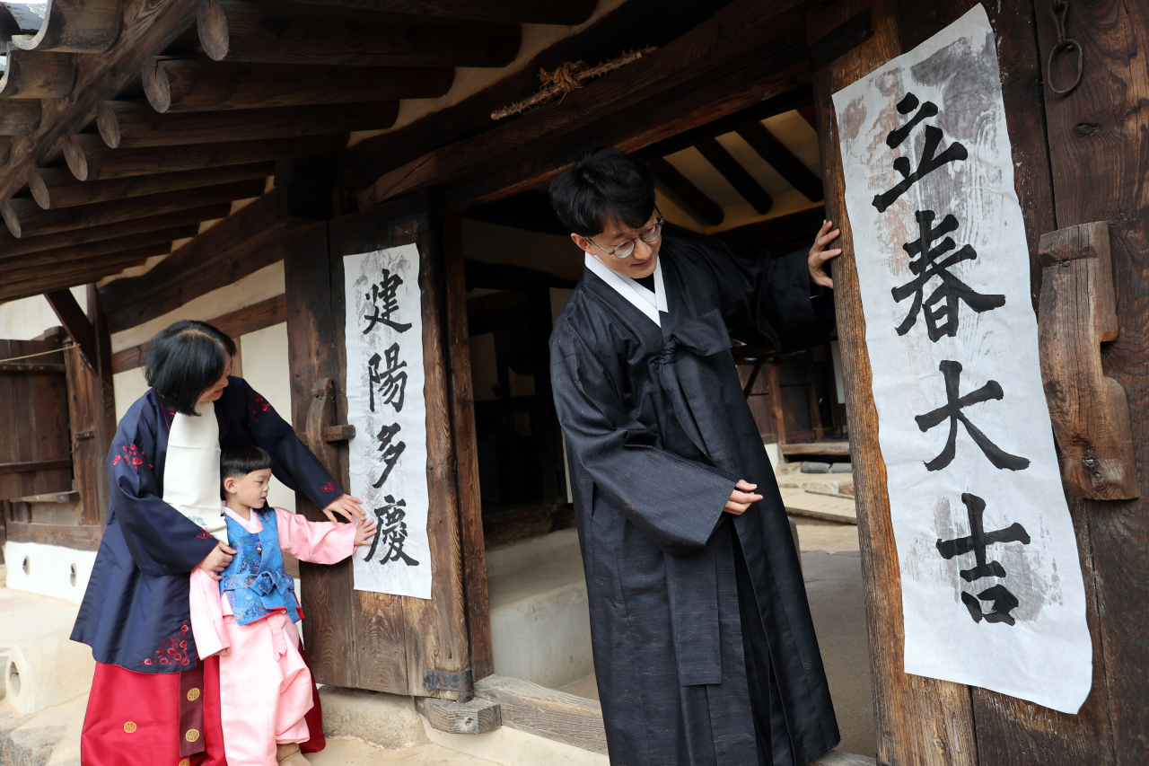 2일 서울 종로구 국립민속박물관에서 열린 입춘 행사에서 행사 관계자들이 오촌댁 대문에 '입춘대길 건양다경'이라고 적힌 입춘첩을 붙이고 있다. [연합]