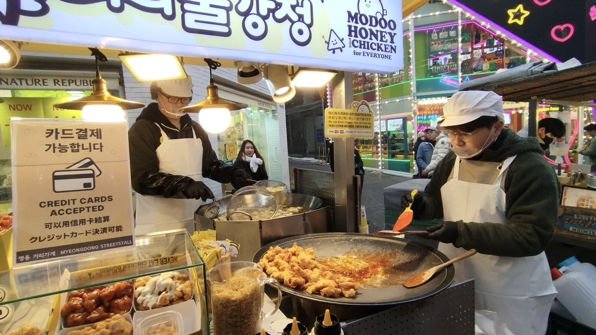 Myeongdong street food vendors at night with colorful carts selling tornado potatoes, egg bread, and tteokbokki to tourists