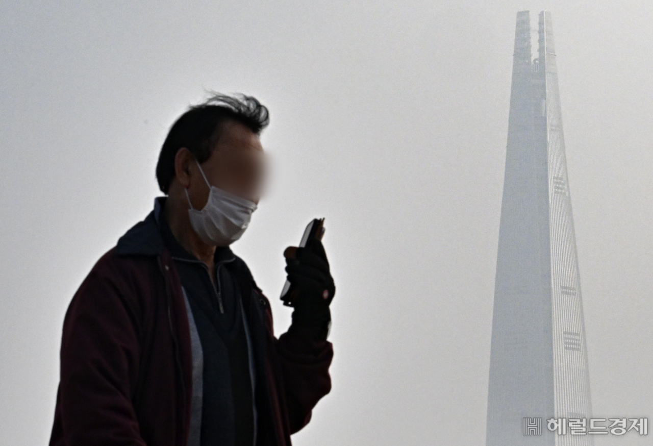 서울 광진구 뚝섬한강공원에서 산책하는 시민 뒤로 롯데월드타워가 미세먼지로 인해 뿌연 모습을 보이고 있다. 임세준 기자