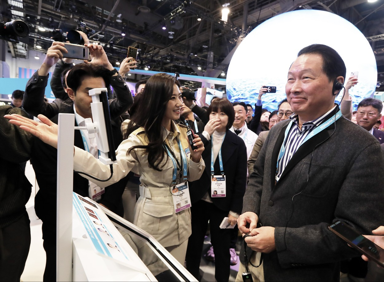 최태원 SK그룹 회장이 지난 1월 미국 라스베이거스에서 열린 세계 최대 전자 박람회 CES 2024 SK 전시관에서 ‘AI(인공지능) 포춘텔러’에 대한 설명을 듣고 있다. [SK 제공]