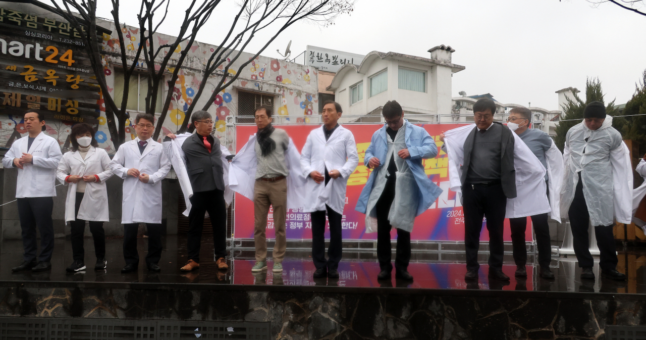 전라북도의사회가 15일 전북 전주시 완산구 전동 풍남문광장에서 열린 의대 정원 증원 반대 집회에서 의사 가운을 벗는 퍼포먼스를 하고 있다.[연합뉴스]