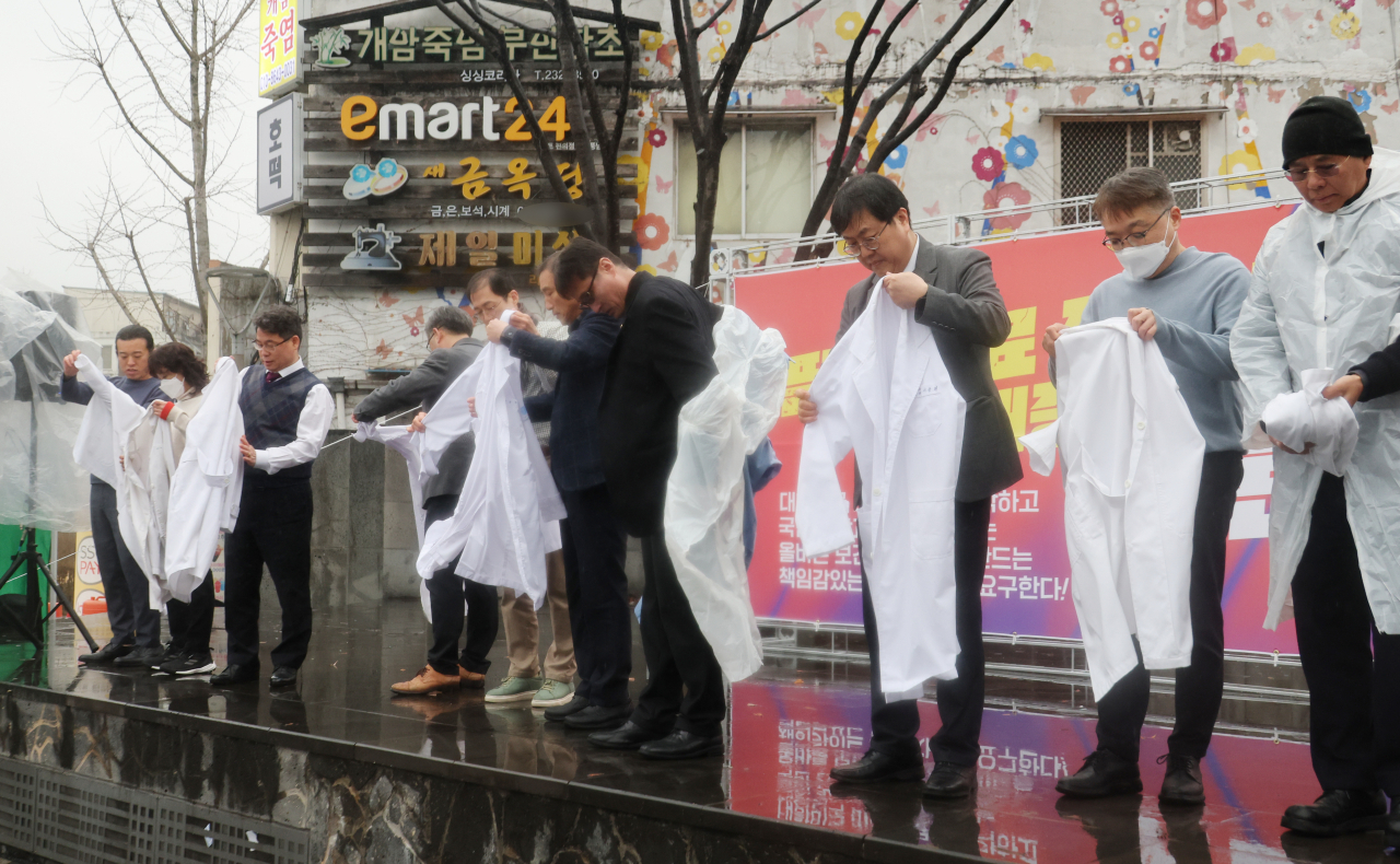 전라북도의사회가 15일 전북 전주시 완산구 전동 풍남문광장에서 열린 의대 정원 증원 반대 집회에서 의사 가운을 벗는 퍼포먼스를 하고 있다.[연합]