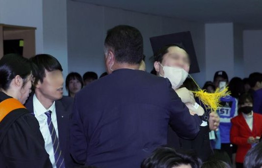지난 16일 대전 유성구 카이스트(KAIST)에서 열린 2024년 학위수여식에서 한 졸업생이 갑자기 자리에서 일어나 윤석열 대통령에 항의하다 제지 당해 끌려나가고 있다. [뉴시스]