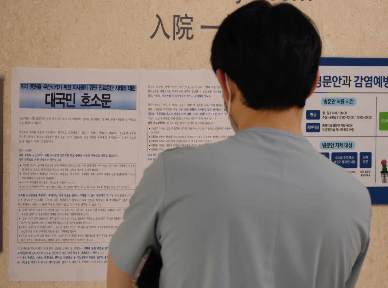 의과대학 정원 확대에 반발하는 전공의의 집단 사직으로 '의료 대란'이 가시화한 가운데 지난 20일 오후 부산 서구 부산대병원에서 한 의료진이 전국보건의료산업노조가 작성한, 의사들의 집단 진료 중단 사태에 대한 대국민 호소문을 읽고 있다.[연합]