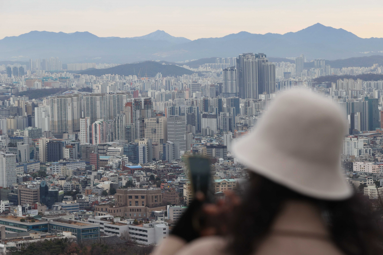 서울 남산에서 젊은 여성이 아파트 밀집지역을 스마트폰으로 찍고 있다. [연합]