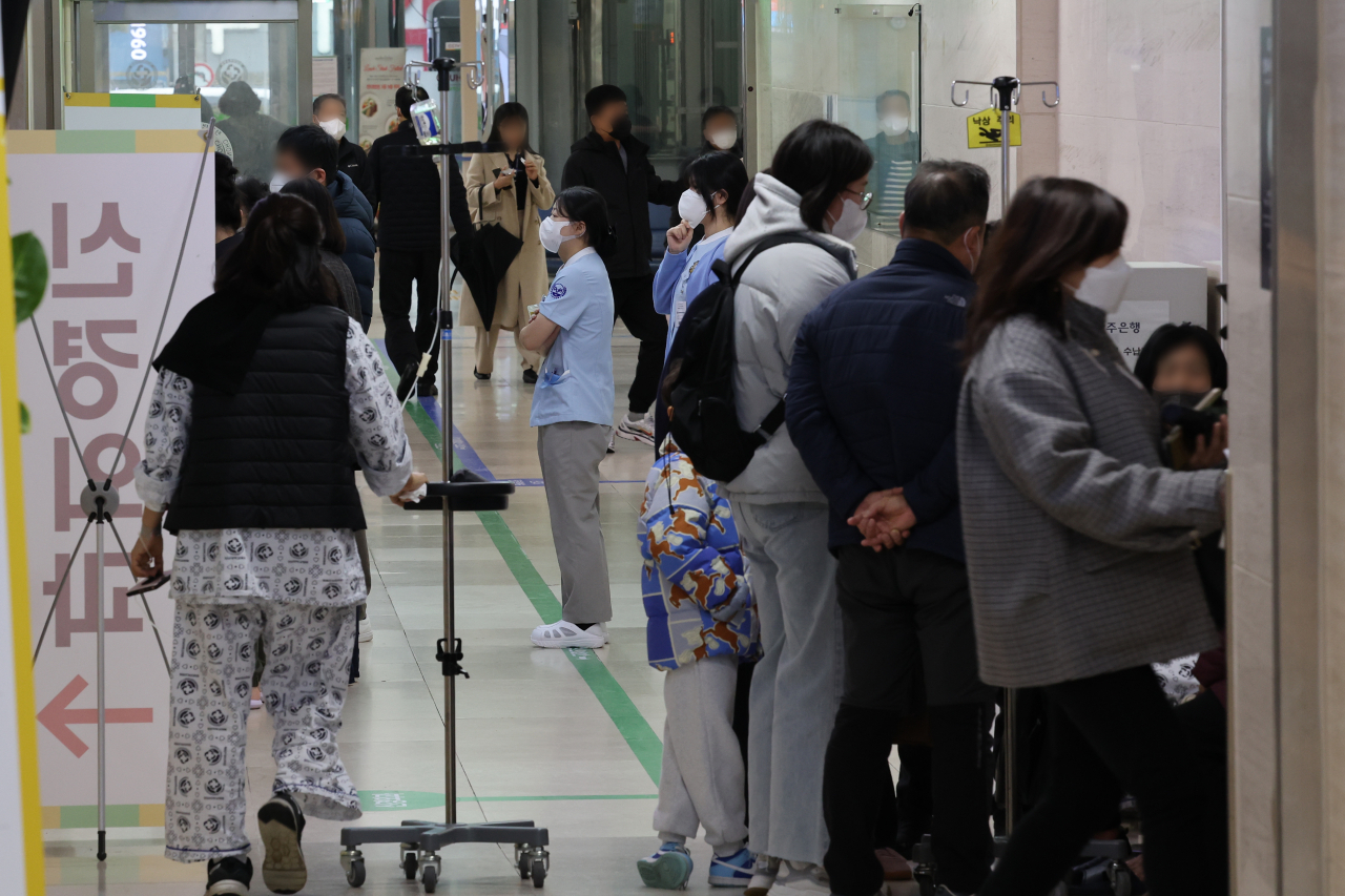 정부의 의대 증원 추진에 반발하는 전공의들의 집단 이탈이 나흘째 이어진 23일 오전 광주 동구 학동 전남대학교병원 본관에서 진료 순서를 기다리는 내원객 사이로 입원 환자가 걸어가고 있다.[연합]