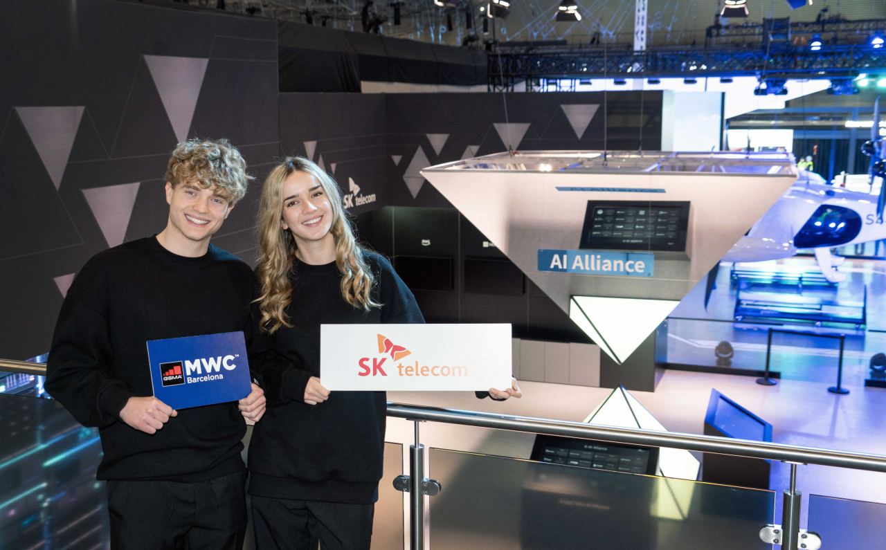 MWC24 SKT 전시관에 마련된 글로벌 텔코 AI 얼라이언스(GTAA) 조형물을 배경으로 포즈를 취한 현지 모델들.[SK텔레콤 제공]