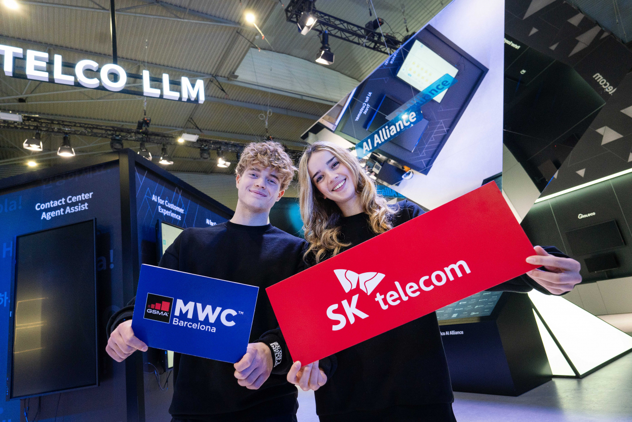 현지 모델들이 MWC24 SKT 전시관에서 텔코(Telco) LLM 관련 전시 조형물을 소개하고 있다. [SK텔레콤 제공]