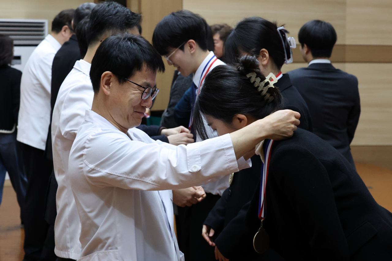 23일 오전 광주 동구 학동 전남대학교 의과대학 명학회관에서 열린 학위수여식에서 교수들이 제자들의 목에 기념 메달을 걸어주고 있다. [연합]
