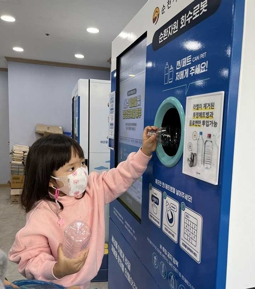 엄마와 함께 온 어린이가 순환자원 회수로봇기에 투명 페트병을 투입하고 있다.