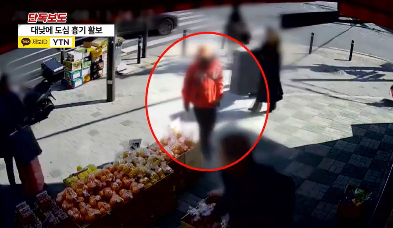 붉은 점퍼를 입은 50대 남성 A씨가 지난 8일 흉기를 들고 서울 강북구의 한 거리를 배회하고 있다. [YTN 영상 갈무리]