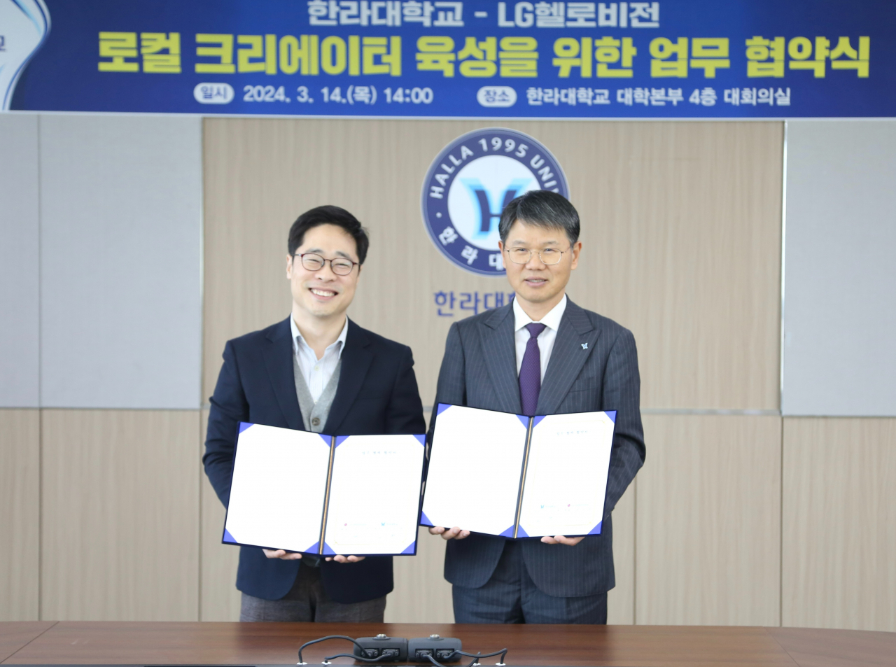 지난 14일 강원도 원주 한라대학교에서 진행된 업무협약식에서 심지훈(왼쪽) LG헬로비전 보도국장과 김응권 한라대학교 총장이 기념촬영을 하고 있다. [LG헬로비전 제공]