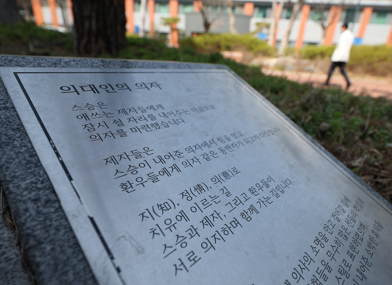 의과대학 교수들의 집단 사직 시한을 일주일 앞둔 18일 대구 한 의과대학 앞 조형물 옆으로 의료관계자가 의대 건물로 이동하고 있다. 연합뉴스