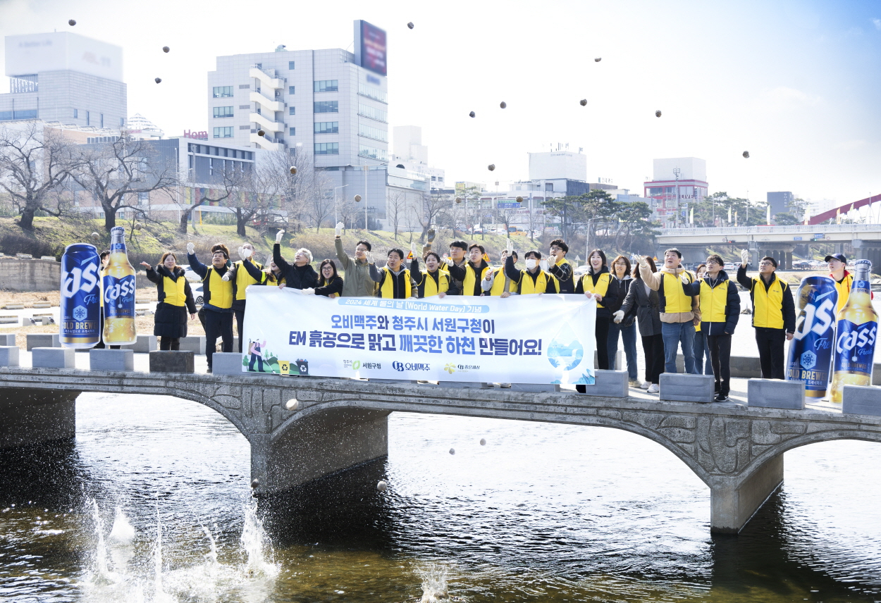 21일 오비맥주 청주공장 임직원들이 서원구청 관계자들과청주시 무심천에서 ‘EM 흙공 던지기’를 하며 하천 정화 활동을 펼치고 있다. [오비맥주 제공]