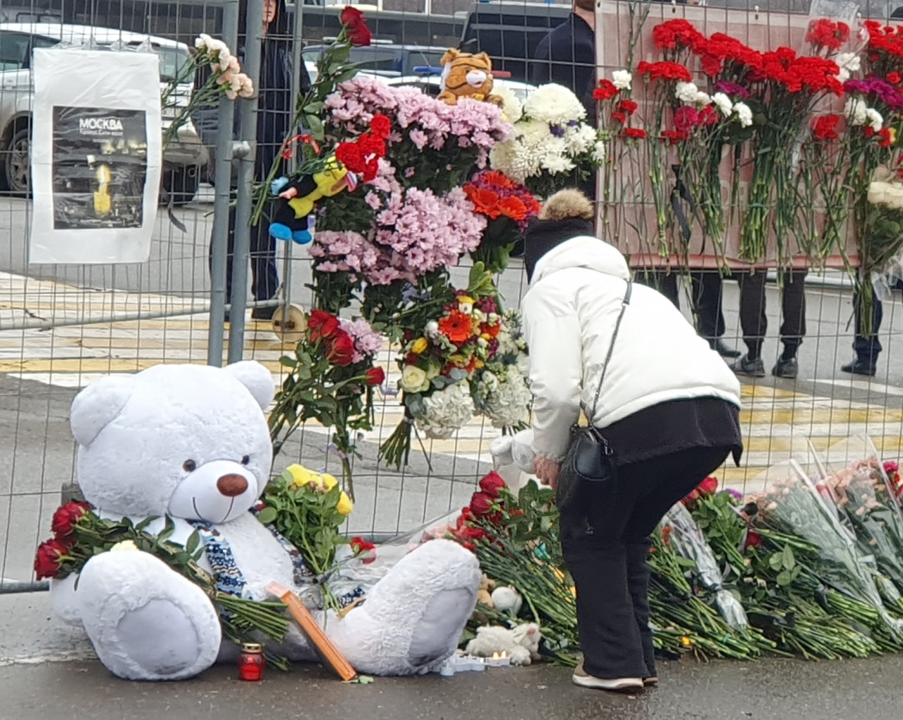 23일(현지시간) 러시아 모스크바 북서부 크라스노고르스크의 '크로커스 시티홀' 공연장 인근에 마련된 무차별 총격 테러 희생자 추모 공간에 애도객이 꽃을 놓고 있다. 이 공간에는 많은 사람들이 두고 간 꽃, 양초, 곰인형이 점점 쌓여갔다. 연합뉴스